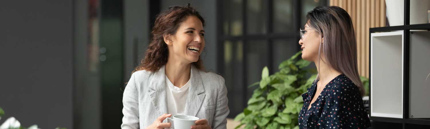 Happy colleagues laughing together during coffee break in work space